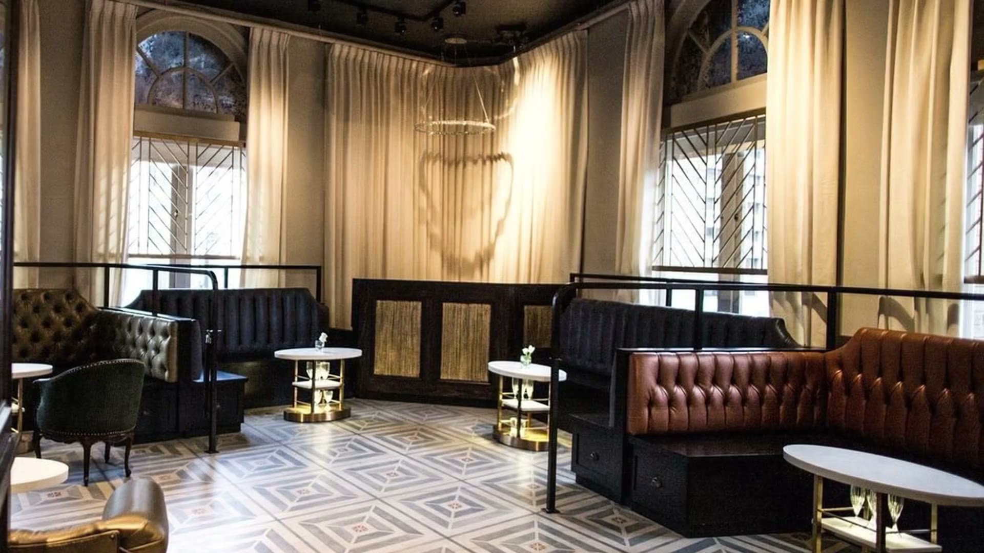 Saint Yves' lounge with tall curtained windows and a tiled floor