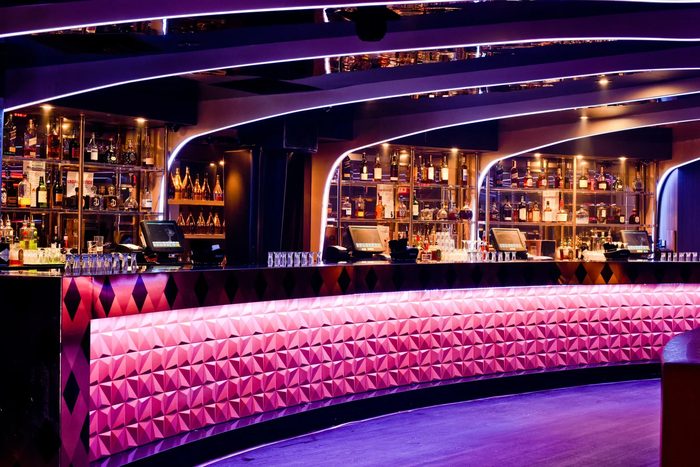 Strand's pink tufted bar under curved lights
